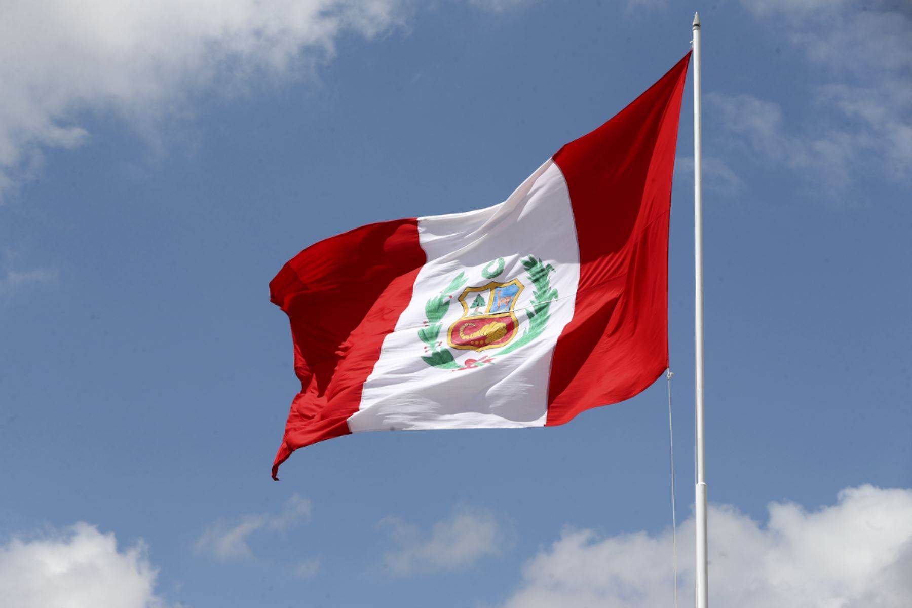 Peruvian flag waving proudly against a blue sky.
